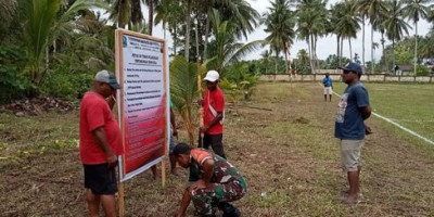 Ringankan Beban Warga, Babinsa Bantu Pasang Spanduk Turnamen Sepak Bola