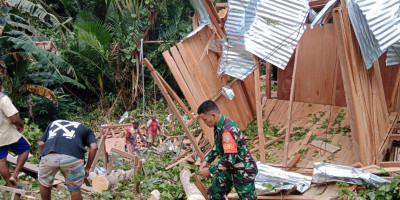 Babinsa Bersama Masyarakat Bersihkan Puing-Puing Runtuhan Bangunan dari Papan Tertimpa Pohon